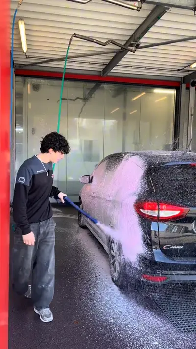 Medewerker schuimt een auto in de wasbox, uit een TikTok-video van Pro Carwash Epe